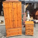 A pine wardrobe and pine bedside chest of drawers.