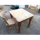 *A small pine kitchen table and two pine chairs.