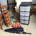 *A set of plastic storage drawers, a shelf unit two umbrellas and some plastic flowers.