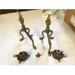 Two brass dog irons, two brass thistle candlesticks and a small brass bust.