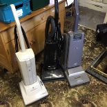 Three upright vacuum cleaners.