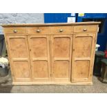 A pine school cabinet with four drawers above four cupboards.