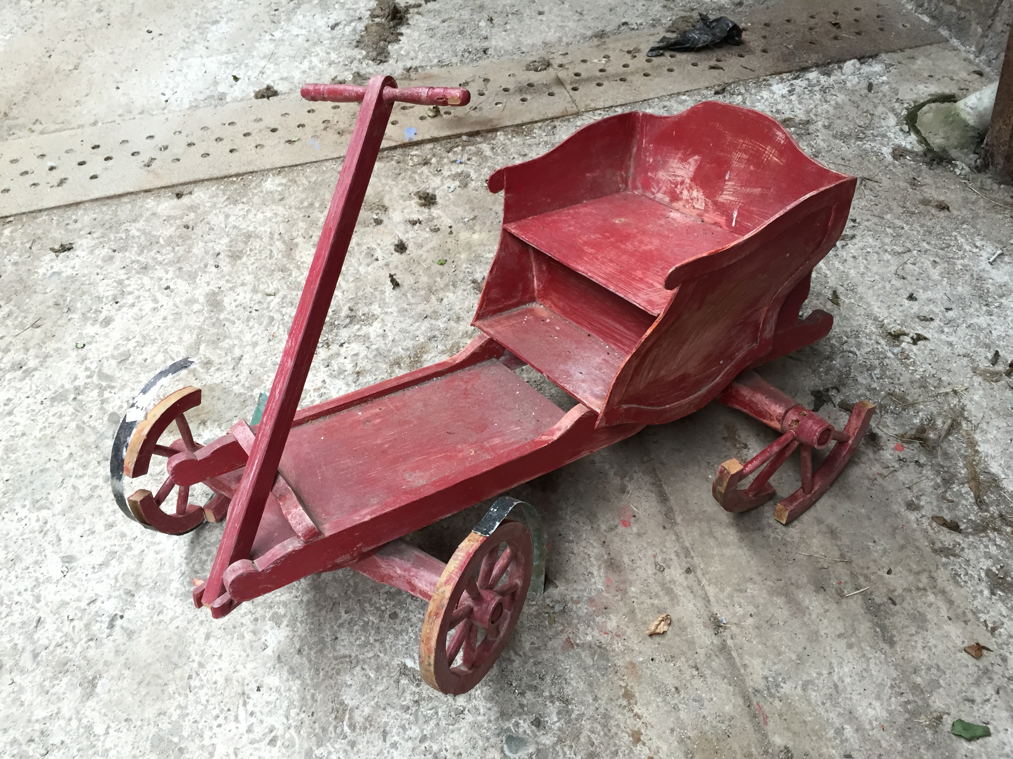 A small child's cart in need of repair.
