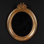 Ovaler Goldstuck-Spiegel mit Bekrönung. Um 1900. Teils polierte Vergoldung. Profilierter Rahmen