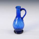 Kleiner Henkelkrug. 19. Jh. Blaues Glas. Birnförmiger, schrägoptisch formgeblasener Krug mit