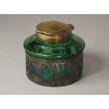 INKWELL.
An Art Nouveau, brass & metal mounted green glass inkwell, the lid with stamped