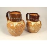 DOULTON STONEWARE.
Two Doulton Lambeth, Victorian 1897, commemorative stoneware jugs.
19 & 17cm.