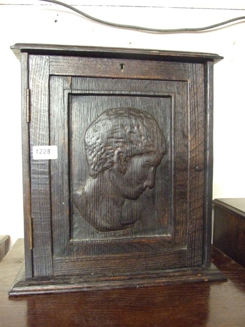 A WALL CUPBOARD WITH CARVED PORTRAIT ON DOOR AND 4 INTERNAL DRAWERS