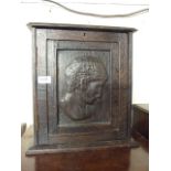 A WALL CUPBOARD WITH CARVED PORTRAIT ON DOOR AND 4 INTERNAL DRAWERS