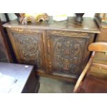 AN OAK STANDING CUPBOARD 44" WIDE WITH LATTICE WOOD WORK TOP, CARVED DOORS ON LOW TURNED LEGS 44"