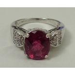 An 18ct gold ring set with a central oval pink tourmaline, on twice stepped shoulders each set with