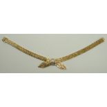 A 9ct textured gold bracelet in a double tied strap design, set centrally with diamonds, on a clip