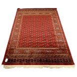 A Bokhara rug with multiple rows of medallions on a red ground, 230 by 160cm.