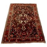 A Hamadan rug with dark red ground, central cream medallion and pendants, black corners, decorated