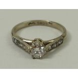 An 18ct gold and diamond solitaire ring, the central diamond, approximately 0.5ct, flanked by three
