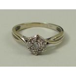 An 18ct gold and diamond flower head ring with seven diamonds, set on twisted shoulders, approx