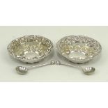 A pair of Victorian silver circular open salts with repousse rococo scroll decoration, and a pair