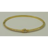 An 18ct gold and solitaire diamond set bangle, approximately 1/8ct, 8.0g.