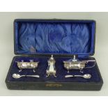 A silver three piece condiment set with spoons and blue glass liners, Birmingham 1942, 3.535toz,