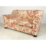 An Edwardian two seater settee with rollover arms, upholstered with red and cream cotton printed