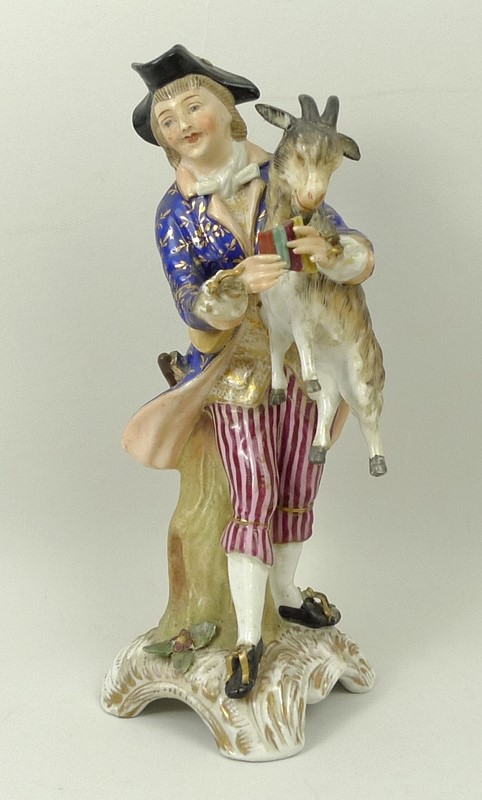 A Sitzendorf porcelain figure, late 19th century, modelled as a boy holding a goat and pan pipes,