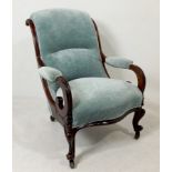 A Victorian mahogany framed nursing chair with carved arms and front legs, terminating on castors,