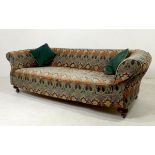 A Victorian three seater sofa upholstered in patterned cotton fabric, raised on turned legs,
