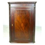 A 19th century mahogany corner cupboard with an inlaid oval shell motif to the door,