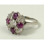 An 18ct white gold, diamond and ruby cluster dress ring, the central diamond, 0.