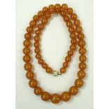 An amber necklace composed of fifty seven graduated spherical cloudy amber beads, 69cm long.