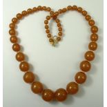 A Russian amber necklace of graduated spherical beads, 63cm long, 71.