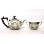 A silver teapot and a matching silver twin handled sugar bowl, each piece of oval form with partly