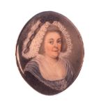 A gold mounted oval portrait miniature of a lady, with curly grey hair, wearing a white bonnet,