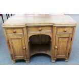 A Victorian pine inverted breakfront desk with three drawers and pair of cupboards about the knee,