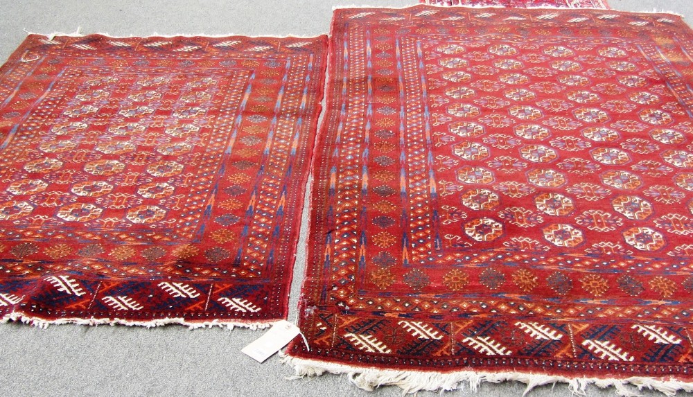An Afghan rug, the madder field with four columns of ten guls, a sunburst border, skirt ends, 244cm