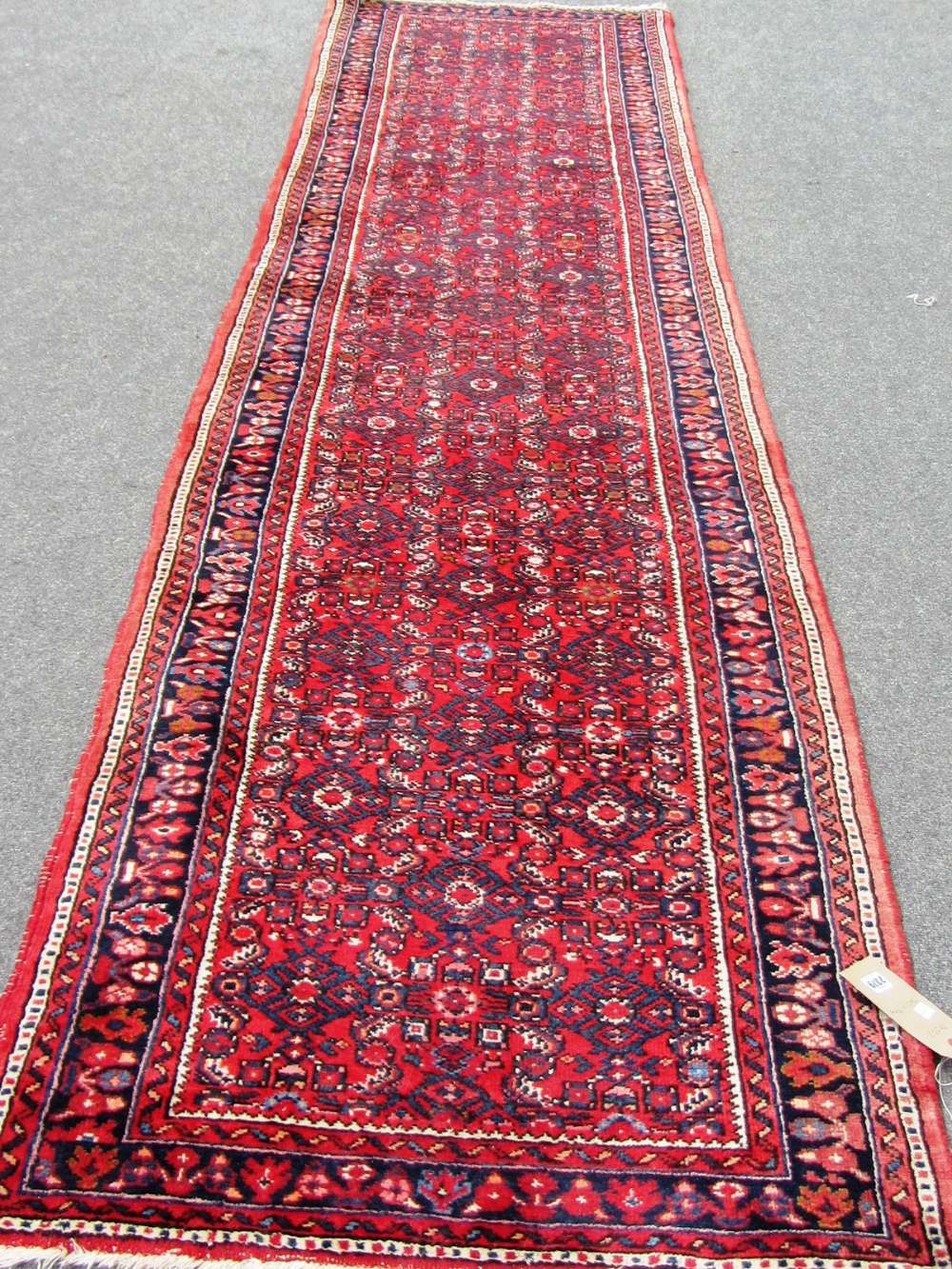 A Hamadan runner, Persian, the madder field with an allover herati design, a dark indigo floral