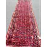 A Hamadan runner, Persian, the madder field with an allover herati design, a dark indigo floral