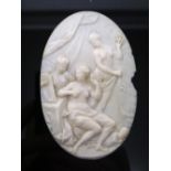 A carved ivory oval plaque, designed as a group of three scantily clad female figures in an