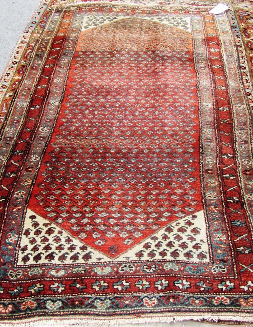 A Bidjar rug, Persian, the madder field with an allover herati design, ivory spandrels, three