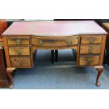 An early 20th century walnut bowfront seven drawer writing desk on cabriole supports, 122cm wide.
