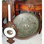 An oak wall mounted barometer and a circular copper charger.