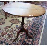 A George III oak tripod table, the circular snap top above a baluster turned pillar, 82cm wide.