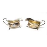 A pair of silver sauceboats, each with a scrolling handle,