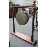 A Burmese oak gong stand with turned frame and brass gong,