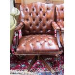 A 20th century studded brown leather upholstered office swivel chair on gilt brass lions paw feet.