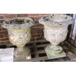 A pair of reconstituted stone garden urns with semi leaf moulded bodies and turned socles,