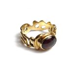 A gold and carbuncle garnet set single stone ring, pierced in a scrolling design,