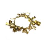 A gold oval link charm bracelet, fitted with a variety of mostly gold pendants and charms,