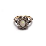 An opal and diamond set oval cluster ring, mounted with the oval opal at the centre,