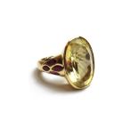 A gold, citrine and garnet set ring, collet set with the oval cut citrine at the centre,